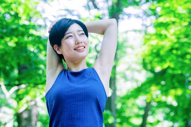 木立の中でストレッチをする女性のイメージ画像